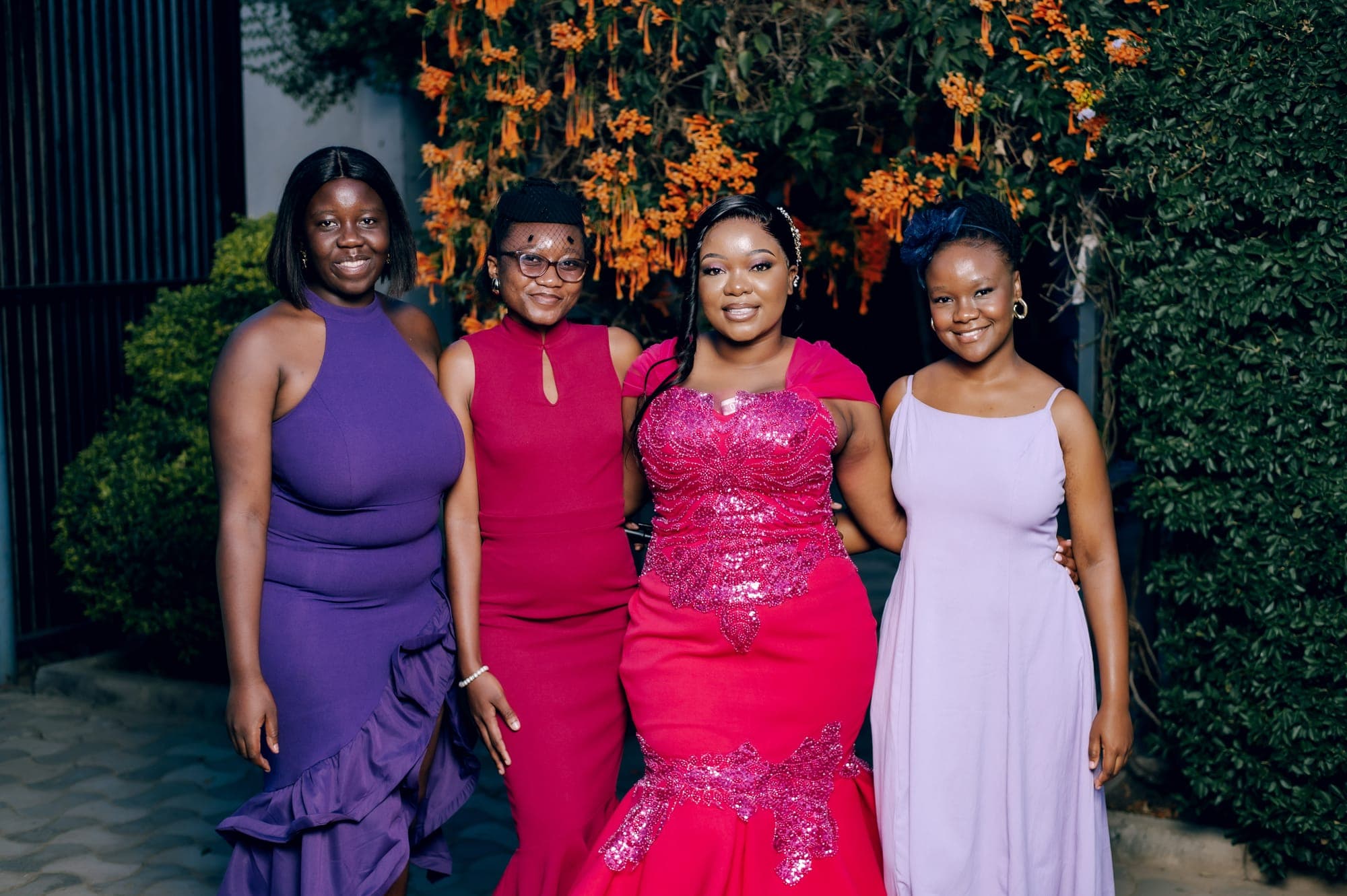 Four guests in jewel-tone dresses at a Lusaka kitchen-party celebration